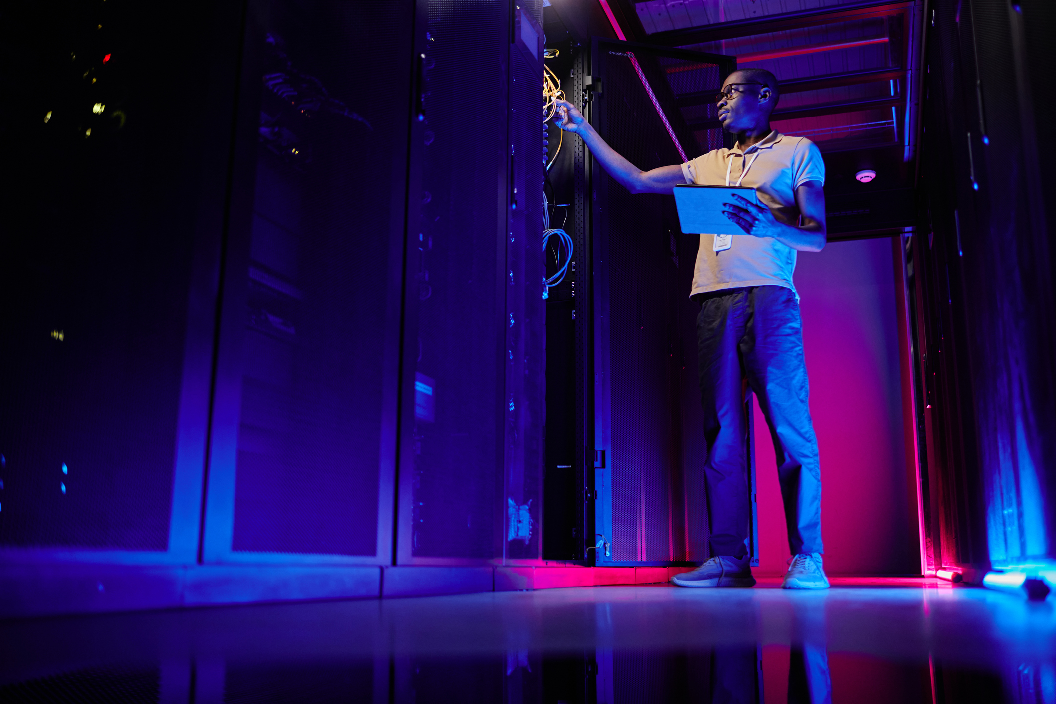 A technician with a managed service provider (MSP) checks connections inside a server room.